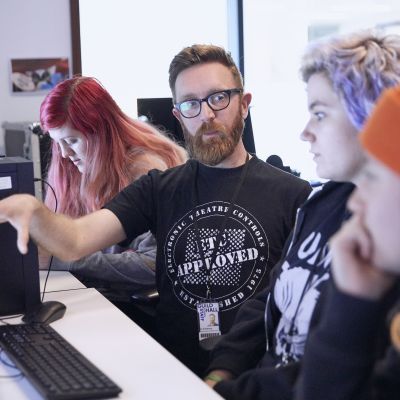 Lecturer teaching students at a computer